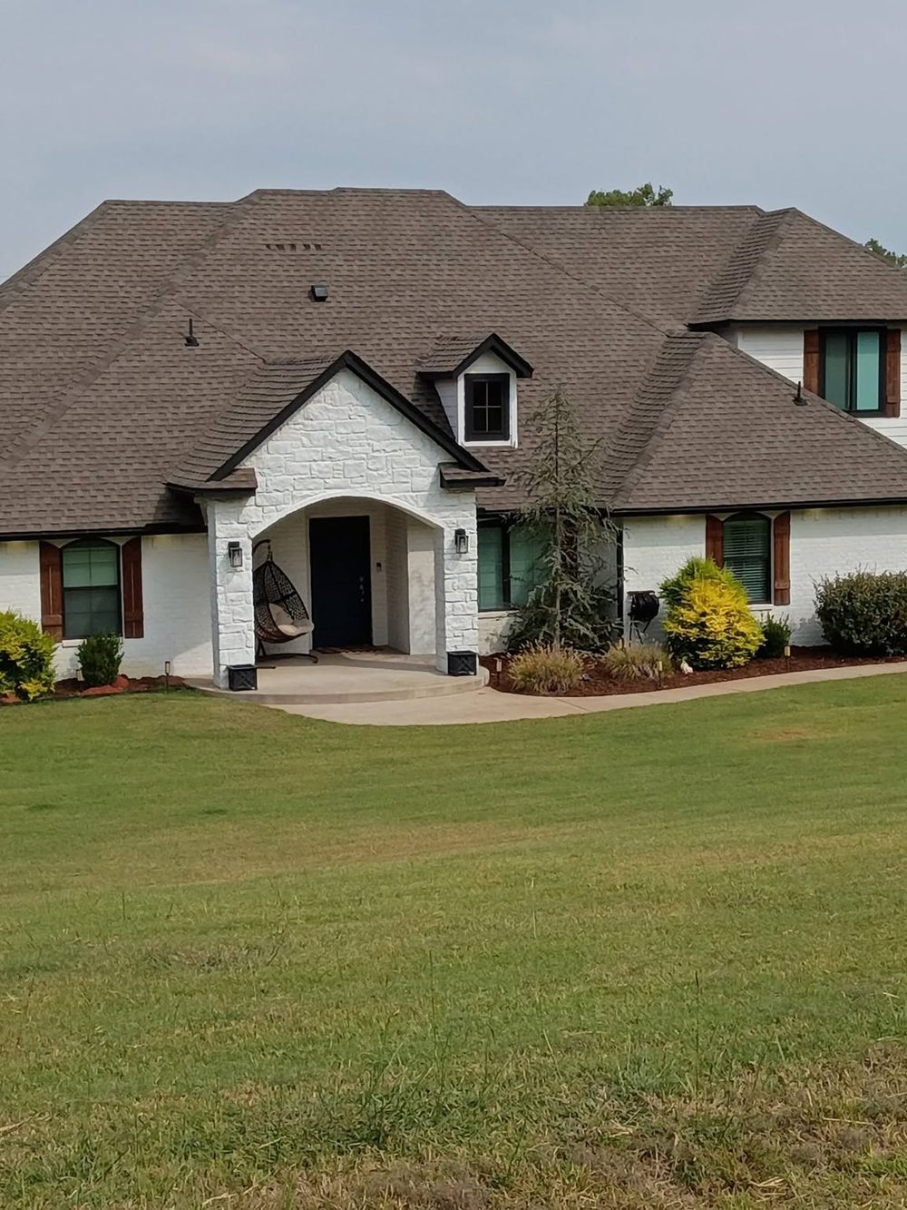 A new shingle roof and gutters on a red barn by CrownRidge Roofco.